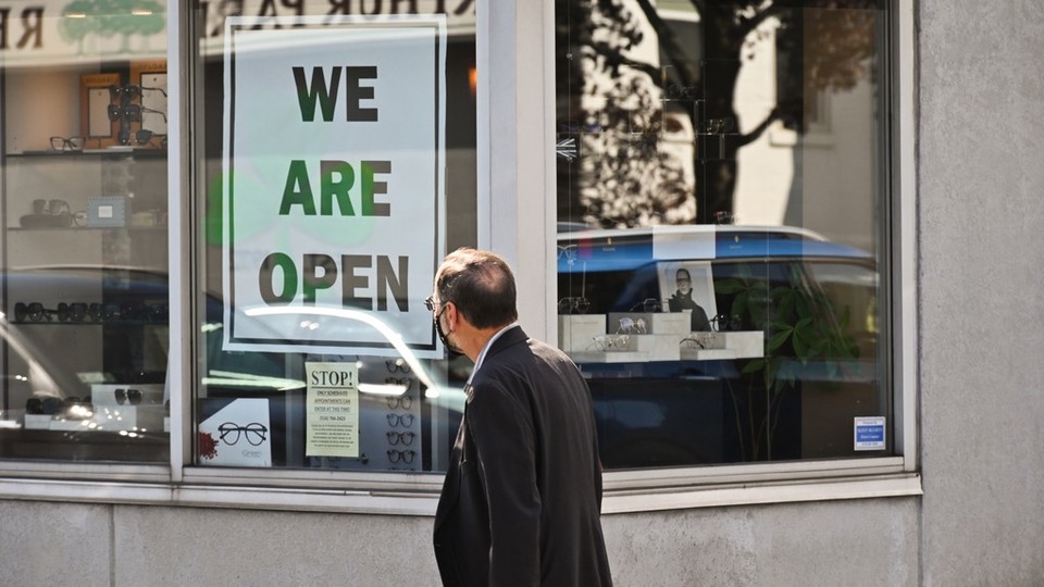 A man walking past a storefront with a “We are open sign.”