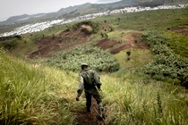 Photo of a Congolese soldier patrolling a hillside covered in vegetation