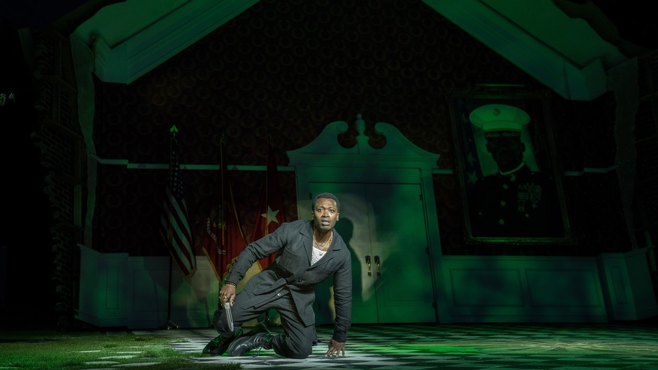 Actor in green light kneeling on ground with a knife