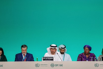 Sultan Al Jaber and other UN leaders sit at a table against a green background