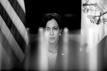 A back-and-white photo of Kamala Harris framed by American and Guatemalan flags behind her