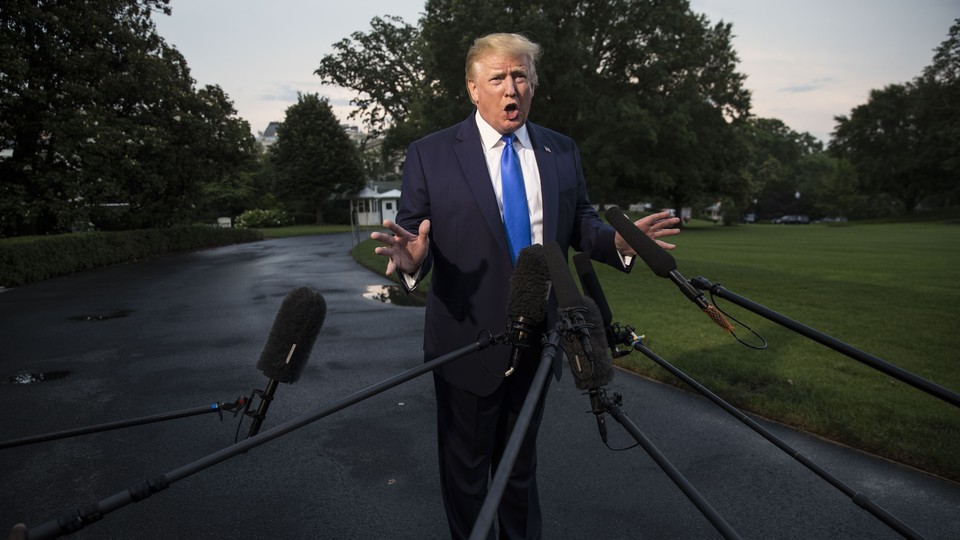 President Donald Trump speaks into press microphones on a White House driveway.