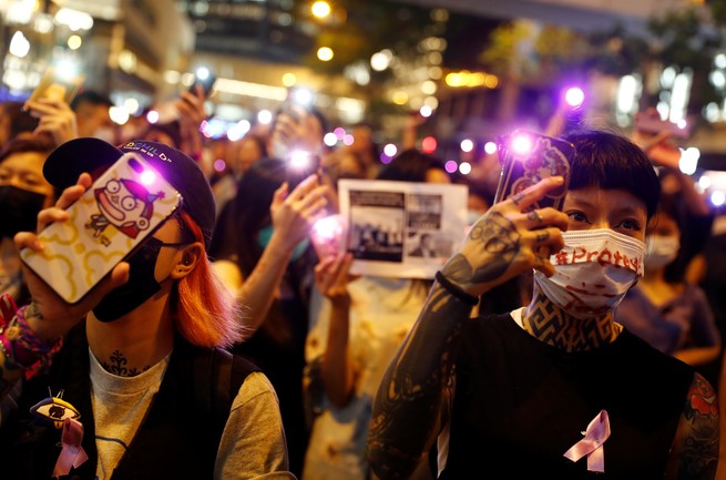Hong Kong protesters hold up their phones and shine violet lights to condemn alleged police violence.