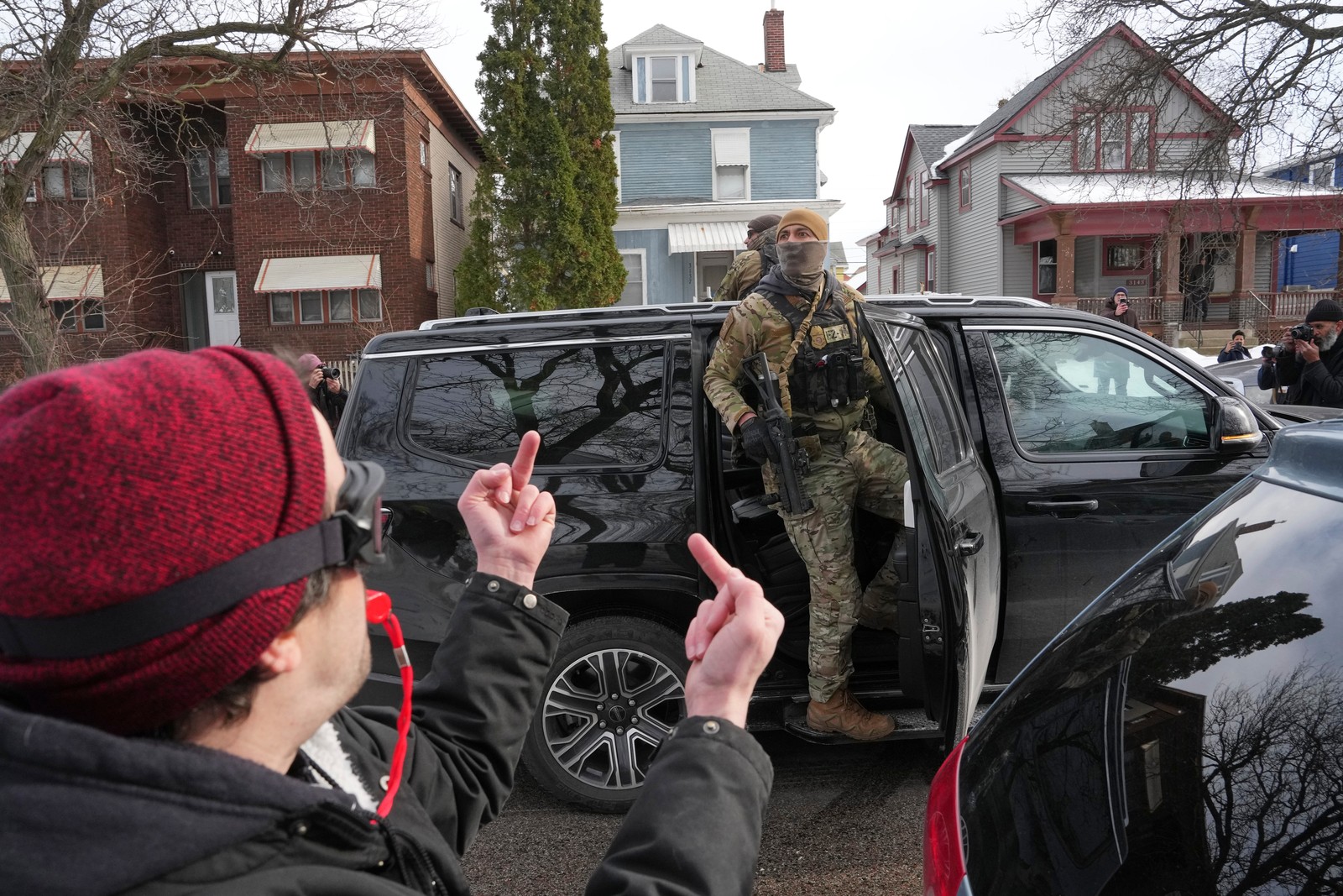 A person makes obscene gestures at armed Border Patrol agents riding in an SUV in a residential neighborhood.