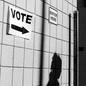 A person walking by a wall with a vote sign
