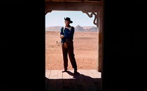 John Wayne stands alone in a doorway
