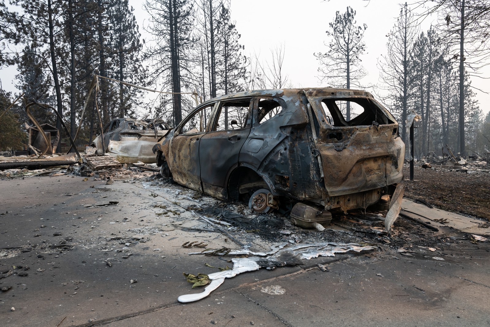 Melted metal sits pooled next to a burned-out car.