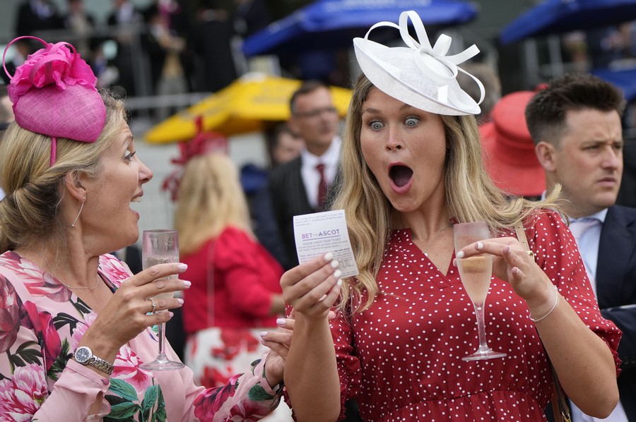 A woman reacts with wide open eyes and mouth to a ticket she holds.