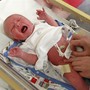 A crying baby is examined in a hospital crib.