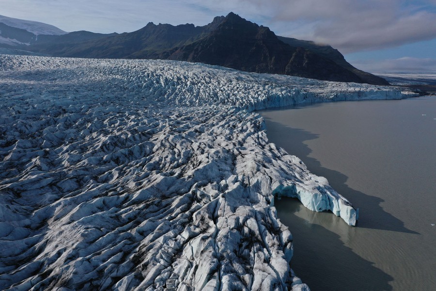 An aerial view of a large glacier ending in a meltwater lake.