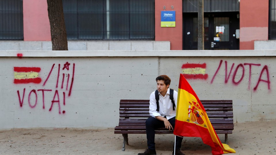 A man holding a Spanish flag sits on a bench before a pro-union demonstration organized by the Catalan Civil Society in Barcelona, Spain on October 8, 2017.