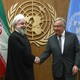 Iran's President Hassan Rouhani shakes hands with United Nations Secretary General António Guterres in front of their respective flags.