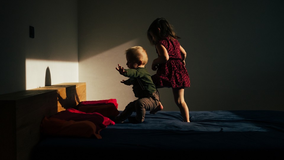 Two children playing on a bed