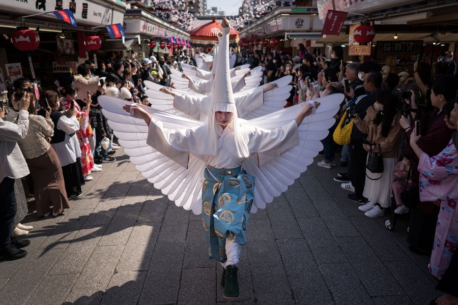 Dancers wearing heron costumes perform in a Tokyo street.