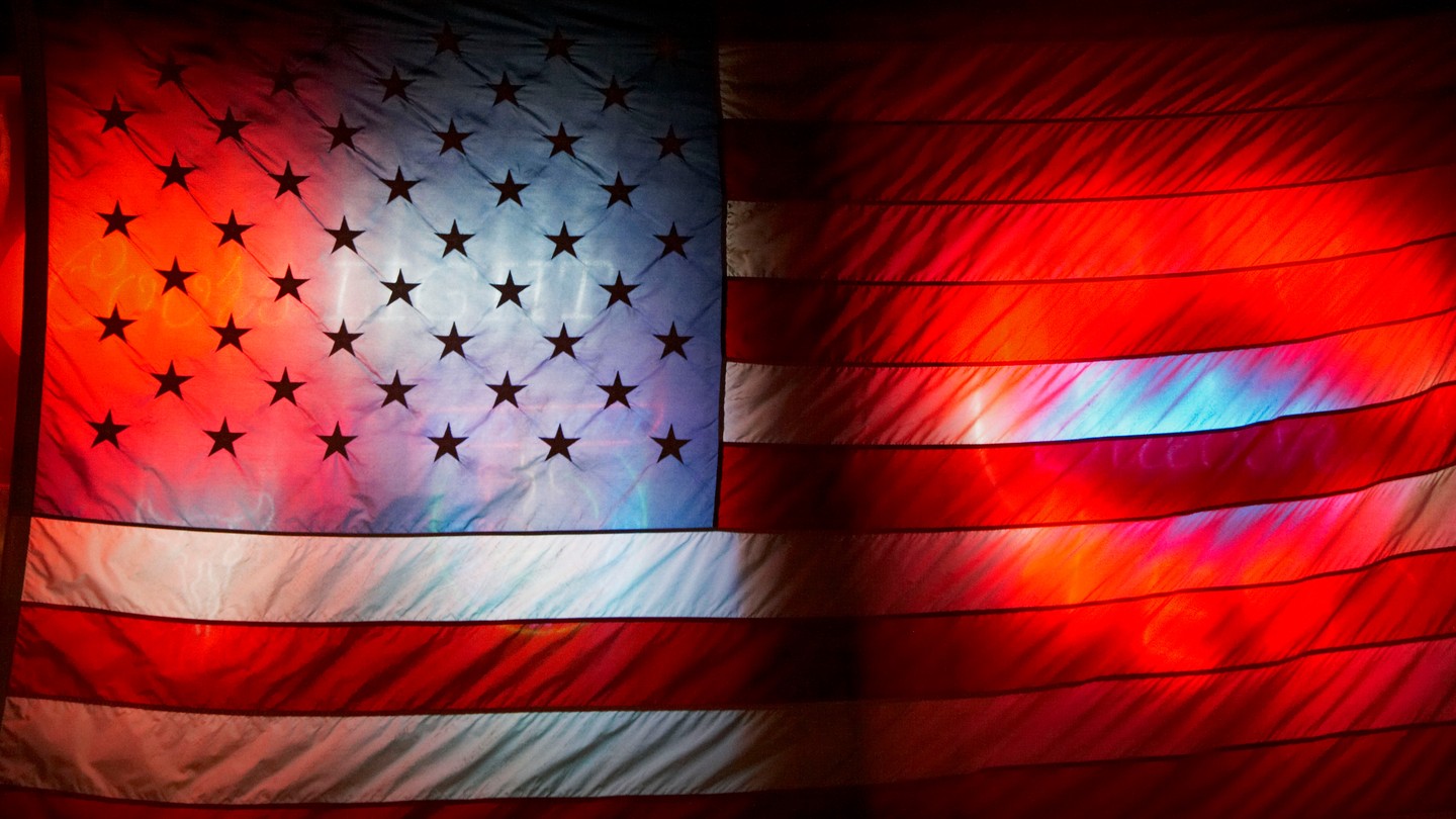 A photo of an American flag with red, white, and blue neon lights shining through it