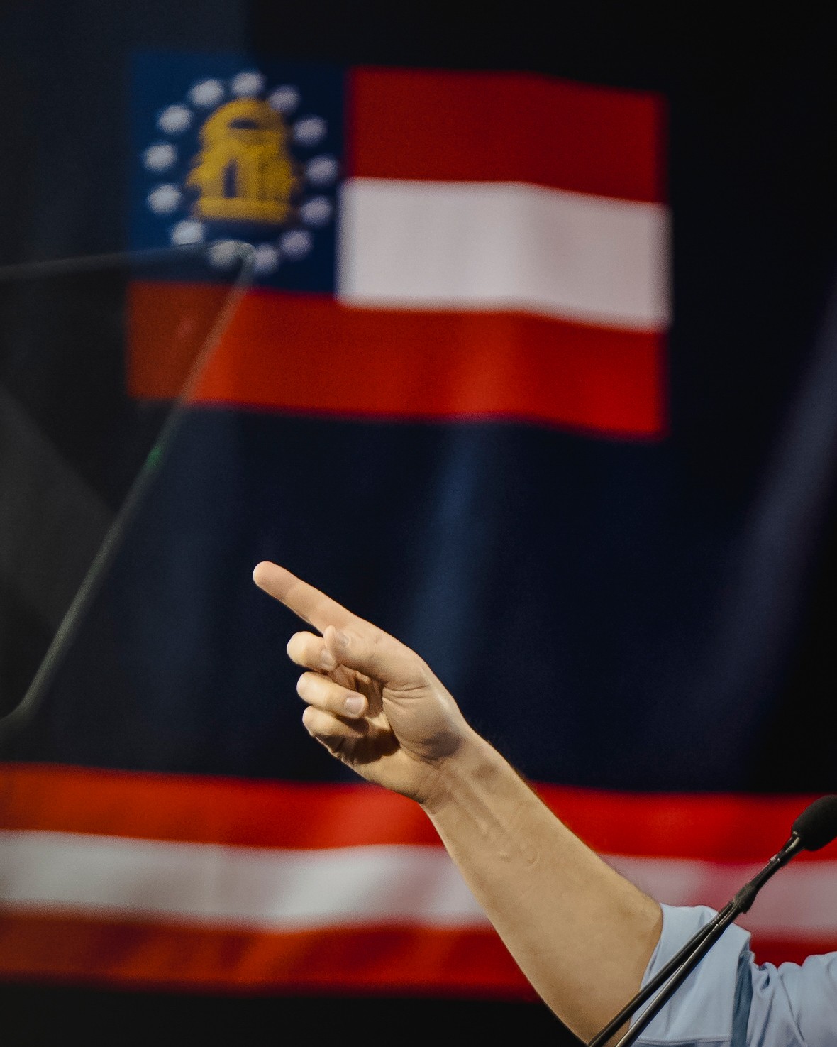a hand points in front of a georgia flag