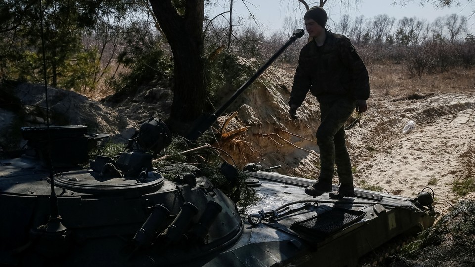 A Ukrainian fighter steps onto a tank.