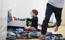 A child pulls clothes out of a drawer.