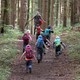 Kids with backpacks running up a forest trail