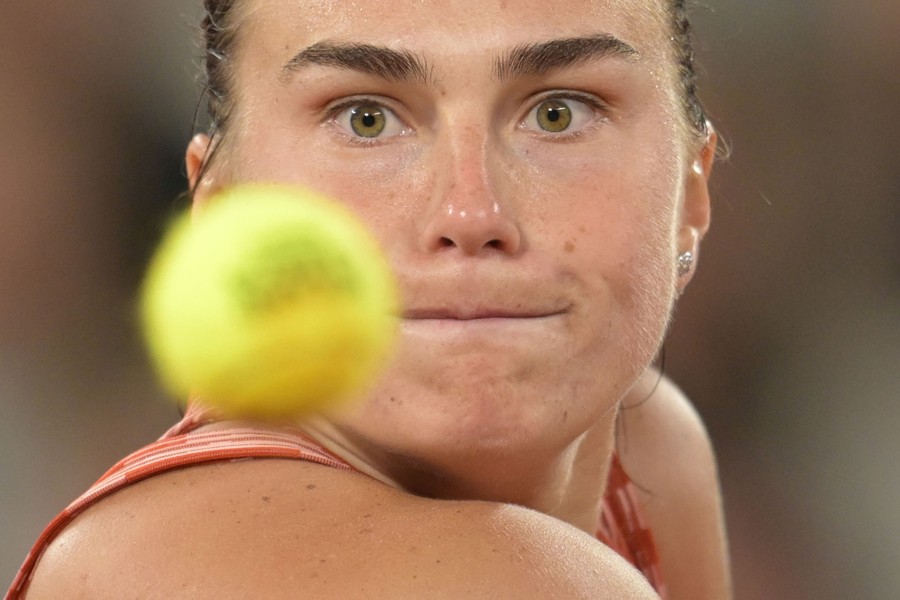 A tennis player looks toward a nearby tennis ball as she prepares to hit it.