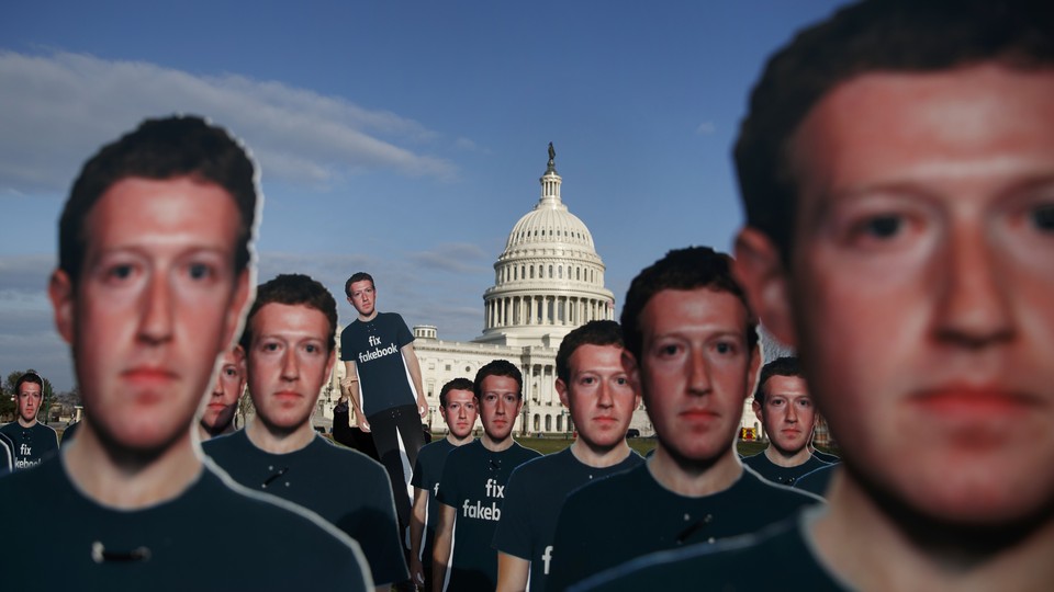 Cardboard cutouts of Mark Zuckerberg's face dominate the foreground, while the dome of the U.S. Capitol looms in the background.