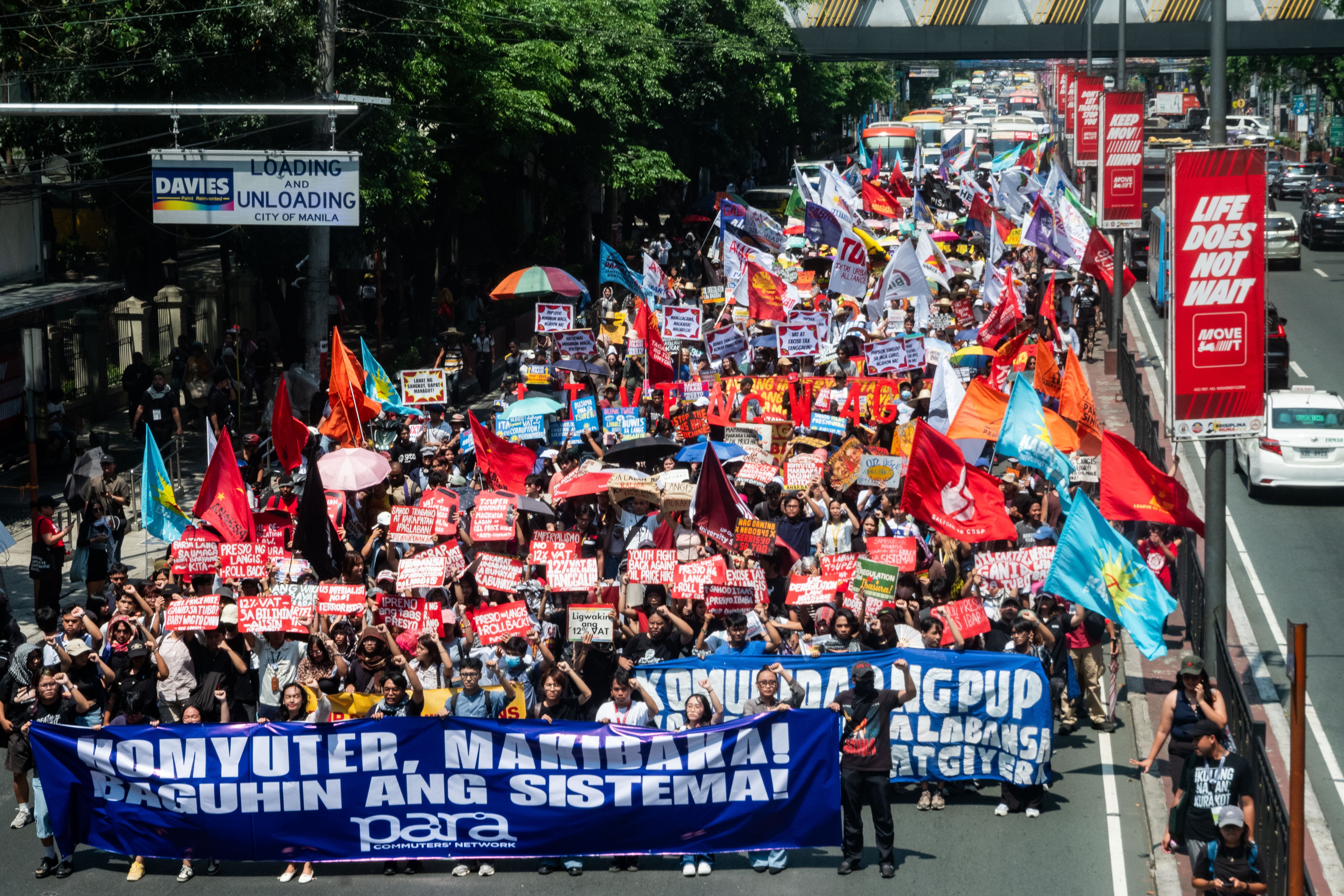 Protesters carry many signs and banners while marching in a street.