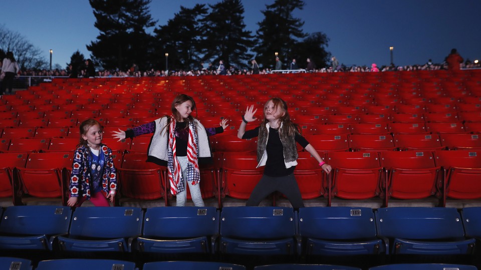 Three girls dance in a stadium full of blue and red chairs as they wait for a Hillary Clinton rally to begin in Philadelphia on Saturday.
