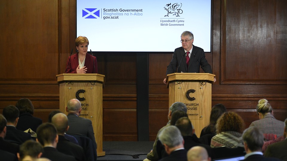 Nicola Sturgeon and Mark Drakeford stand at podiums while delivering a press conference.