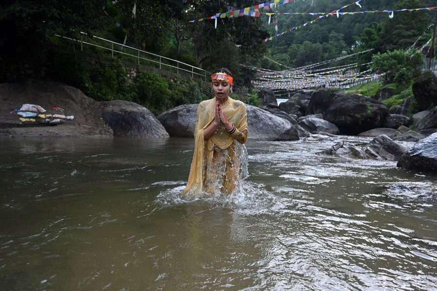 A person offers prayers while standing in a river.