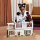 A young child plays with a doll version of her family in a dollhouse