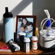 A photo of a framed family photograph, a nebulizer, a Hydro Flask, and bottles of pills on a desk