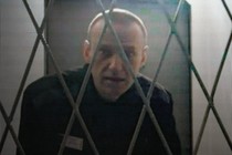 Navalny, behind a security fence, looking at the camera