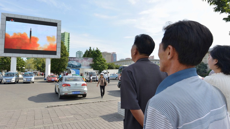 North Koreans watch news report showing North Korea's Hwasong-12 intermediate-range ballistic missile launch on an electronic screen.