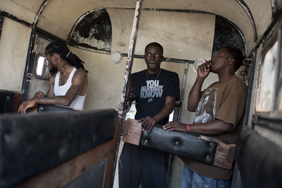 To get shelter from the sun, Jamil Prattis, 26, Stevie Spann, 50, and Nate Benson, 40, sit inside a horse trailer to smoke on Sunday, May 25, 2014. 