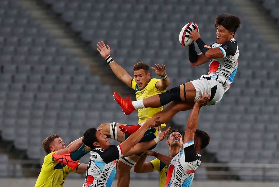 Rugby players leap to catch a ball.