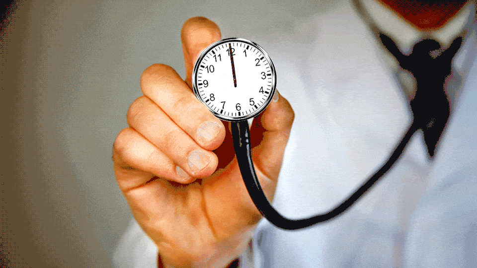 A GIF of a doctor's hand holding up a stethoscope that actually has a ticking clock on its face; the hands are moving around quickly.