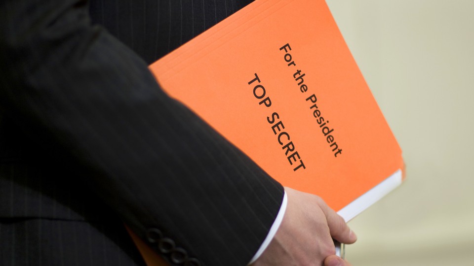 A White House staffer holds a folder with top-secret documents.