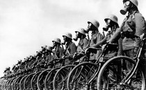 A line of German soldiers wearing gas masks and standing beside their bicycles