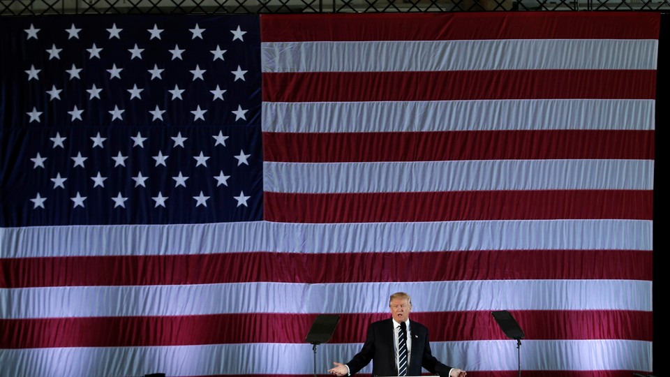 President Trump speaking in front of a large American flag