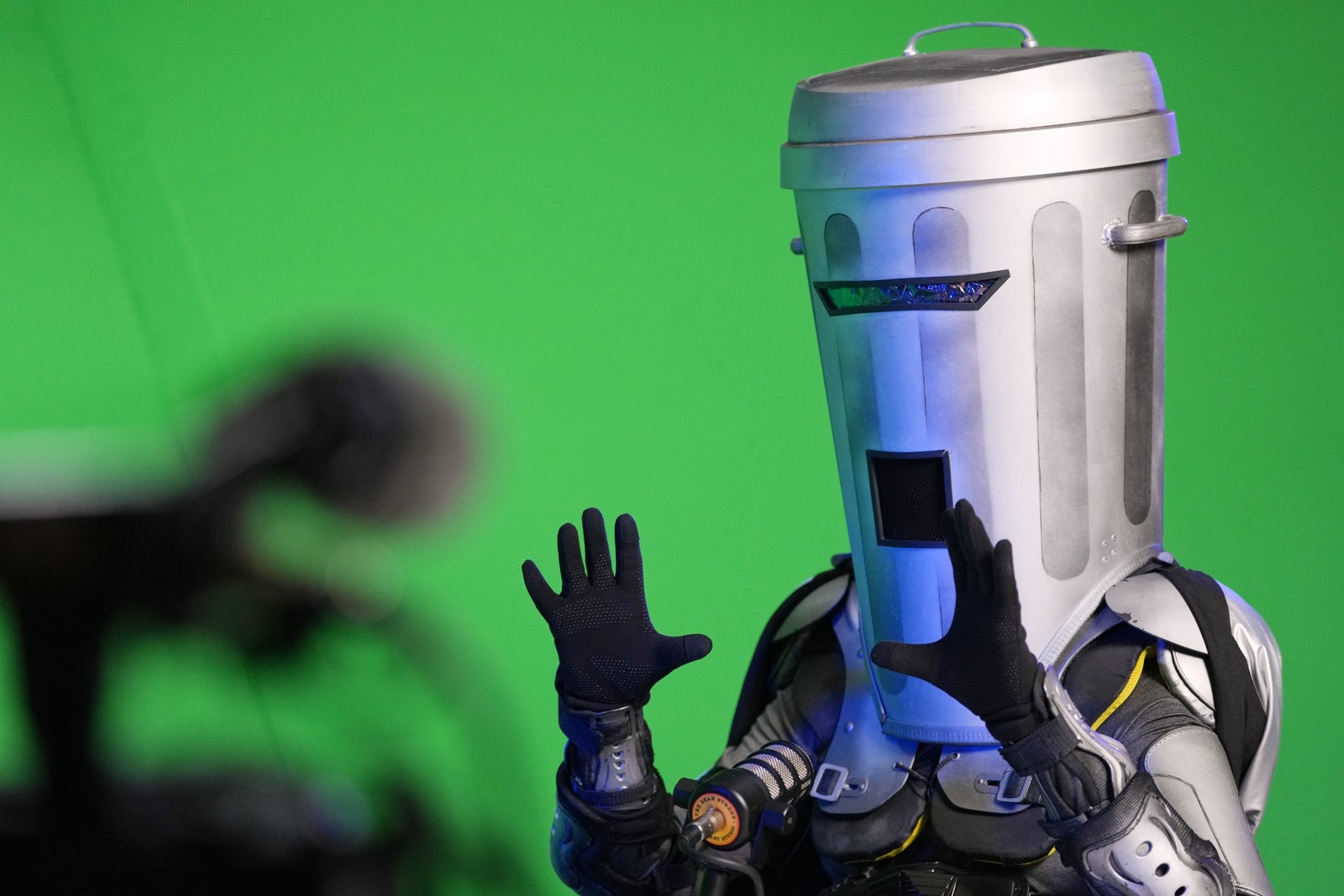 A man wearing a full-head garbage-can mask is interviewed as a candidate before an election.