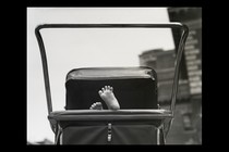 A baby's feet stick out of a stroller in a black-and-white photo.