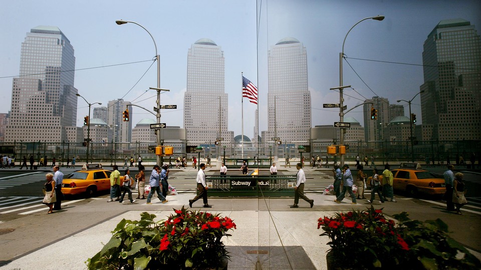 Pedestrians in New York are reflected in a window as they pass the World Trade Center site.