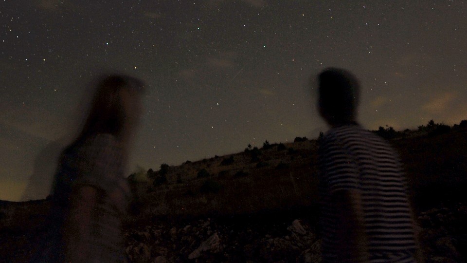 Two blurry figures look at the stars.