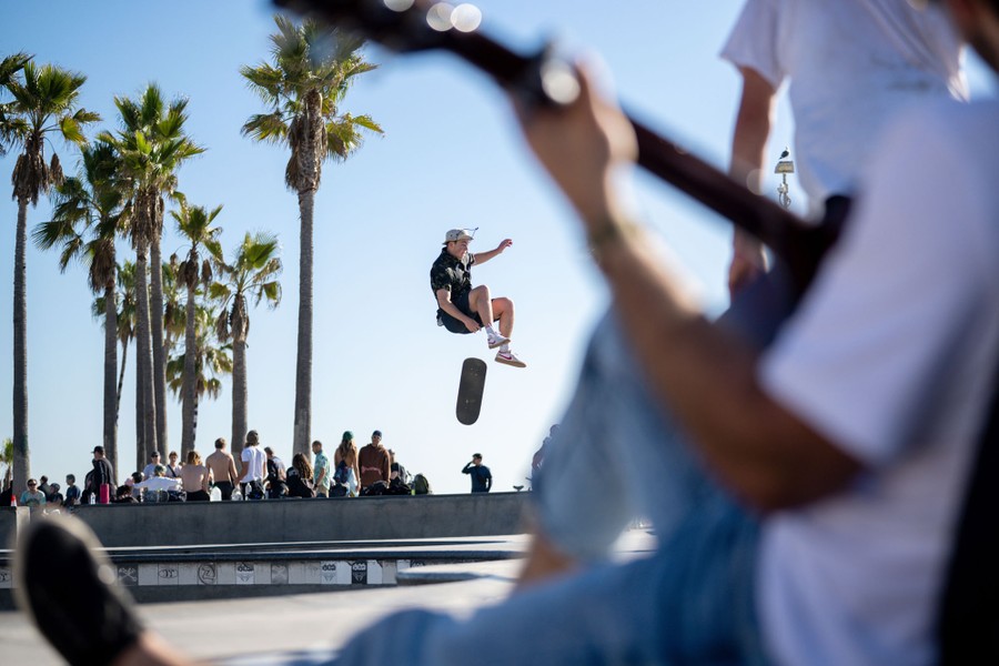 A skateboarder performs a trick at a beachside skate park.