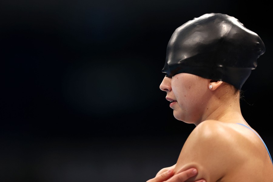 A swimmer with her swim cap pulled down over her eyes prepares for a race.