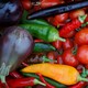 A basket of vegetables, including tomatoes, peppers, and eggplants.