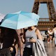 Photograph of women walking with parasols in front of the Efifel tower