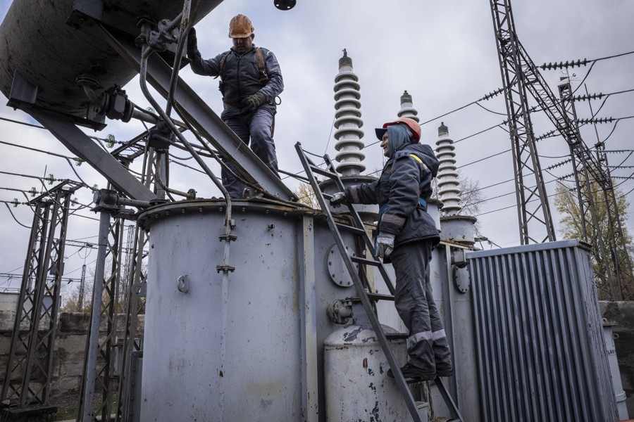 Two utility workers repair damaged electrical equipment.