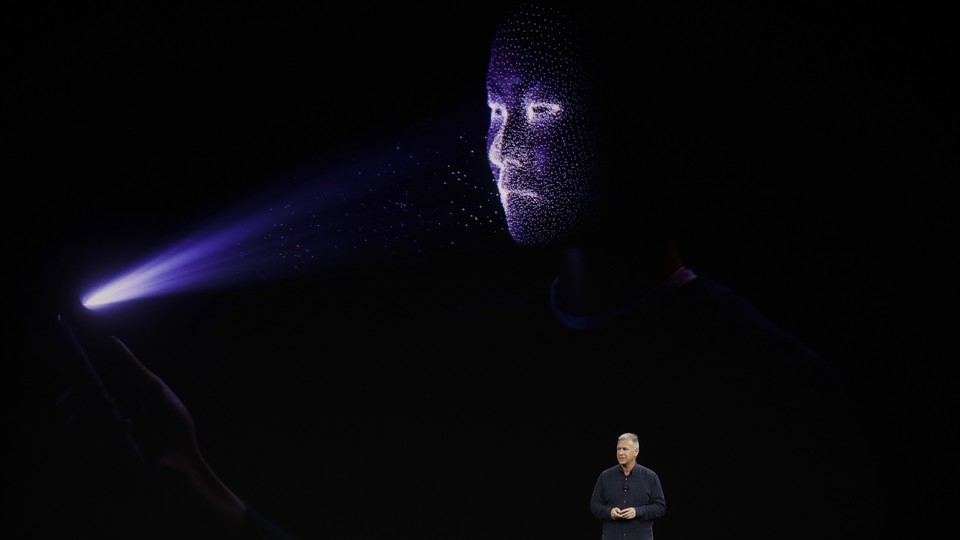 Phil Schiller stands in front of a screen demonstrating the Face ID feature of the iPhone X.