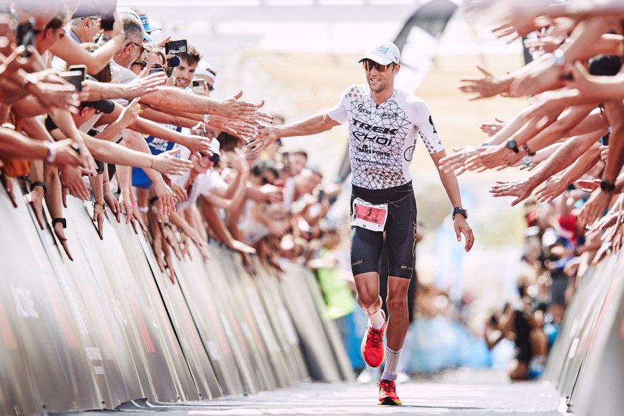 An athlete touches the outstretched hands of many fans as he runs past.